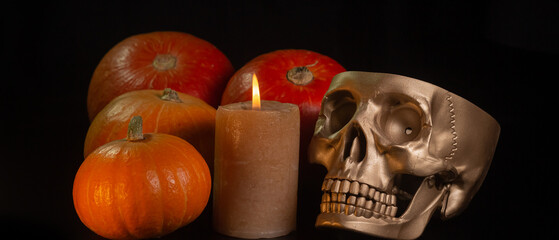 Yellow-orange pumpkins with candles and skulls on a black background the concept of Halloween and the autumn harvest of pumpkin close-up copyspace from above
