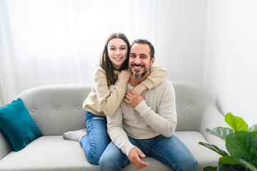 father and teen girl having great time on sofa at home