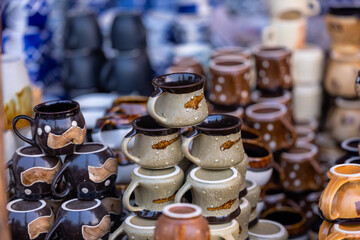 Colorful coffee or tea cups on shelf against ceramic items blur background.