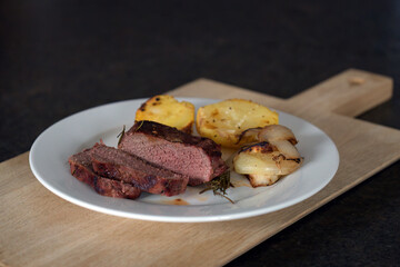 ready to eat -venison from a red deer calf, potaotes and onions grilled of a charcoal grill
