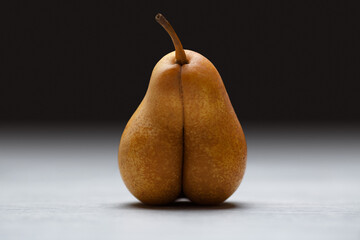 funny yellow pear in the shape of body and genitals . sexuality and food close up portrait on black background with copy space for text. Sex  and erotic concept on grey background.