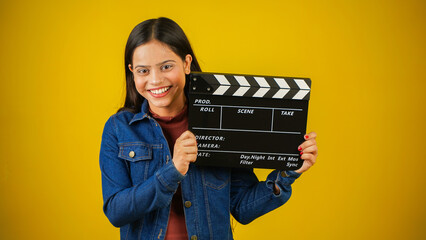 Beautiful young Asian Indian woman standing holding clapperboard, clapper board used in film...