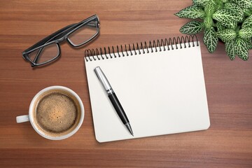 Blank office notebook with pen and cup on the desk