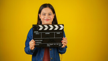 Beautiful young Asian Indian woman standing holding clapperboard, clapper board used in film...