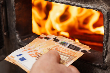 Man throwing euro money in the boiler with bright flames in it. Concept of high prices for heating...