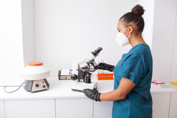 woman bio laboratory technitian placing a glass slice on a microscope  - obrazy, fototapety, plakaty