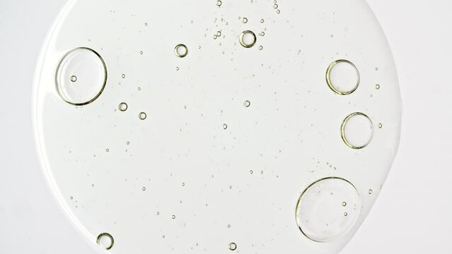 Transparent cosmetic gel fluid with molecule bubbles oil distribution on a white background. Macro Shot of Natural Organic Cosmetics, Medicine. Production Close-up. Slow Motion. High quality 4k