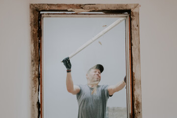 A man working with a crowbar in a doorway.