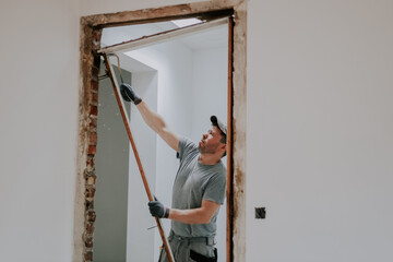 A man working with a crowbar in a doorway.