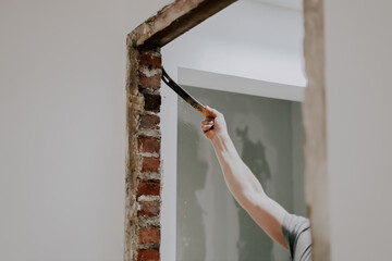 A man working with a crowbar in a doorway.