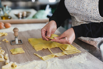 Senior woman working inside pasta factory while doing fresh made traditional italian ravioli
