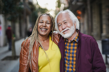 Senior multethnic couple smiling on camera during travel vacation in the city