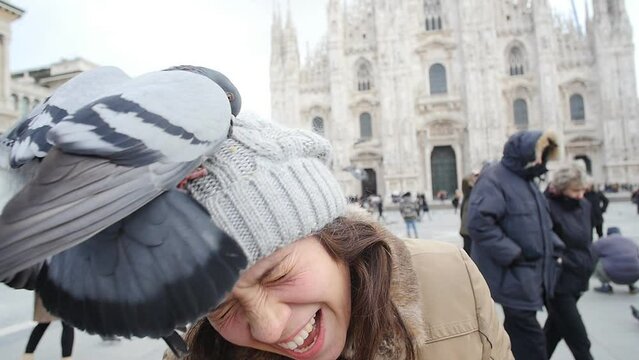 Happy tourist and pigeons in a a front of Duomo cathedral, Milan. Winter travel concept