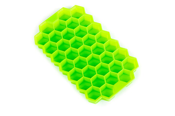 green silicone mold on a white background. the mold is designed for freezing ice. a small shadow along the edge of the form. ice in the form of honeycombs.