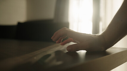 Man finger tap on walnut wood table indoor