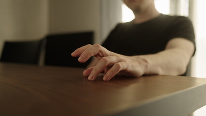 Man finger tap on walnut wood table indoor