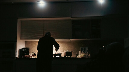 Man cooking with flashlights on a kitchen during blackout in ukraine. Blackout in Ukraine concept....