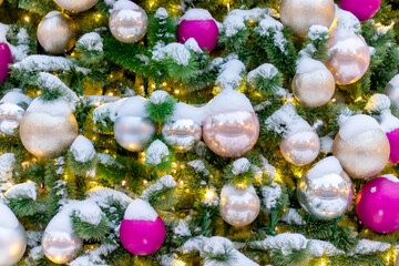 Winter background of Christmas tree toys on the branches of a Christmas tree covered with snow. Close-up.
