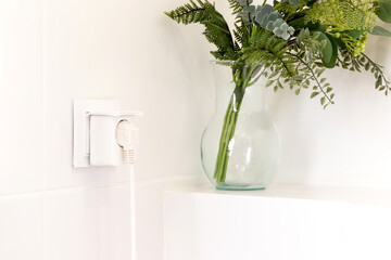 White european electrical outlet with smart plug inserted into it on modern bright bathroom with...