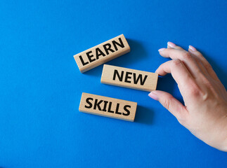 Learn new skills symbol. Concept words Learn new skills on wooden blocks. Beautiful blue background. Businessman hand. Business and Learn new skills concept. Copy space.