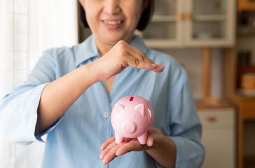 Obraz na płótnie Canvas Elderly woman holding piggybank. Saving and investment for future concept