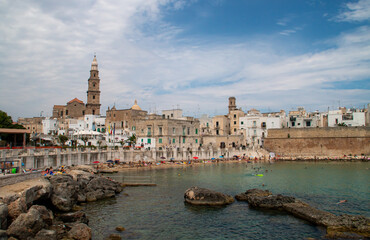 Muralla defensiva y casco antiguo junto a la playa de Porta Vecchia en Monopoli, Italia....