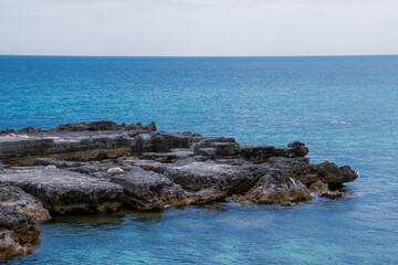 Bañista haciendo snorkel en la cala de Porta Vecchia en Monopoli, Italia. Agua azul turquesa de la rocosa costa del mar Adriático en verano.