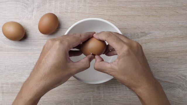 Close up hand crack chicken in to a bowl for cooking scrable egg. Cooking breakfast concept.