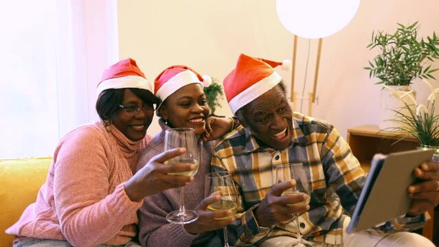 senior african american family in santa claus hats drinking champagne talking meeting friends on virtual zoom video call celebrating new year party, senior parents with their daughter