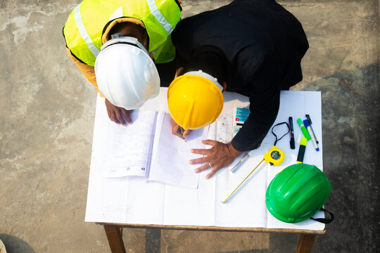 top view of construction engineer draftsman with supervisor at construction site working on drawing blueprint