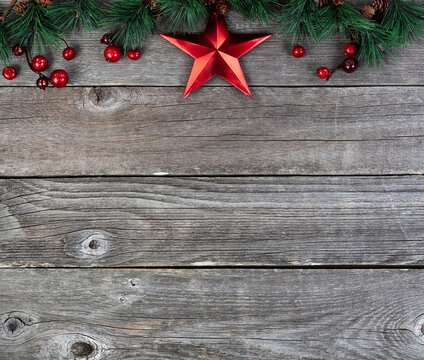 Merry Christmas or happy New Year background with fir tip branches and red star decoration on rustic wood