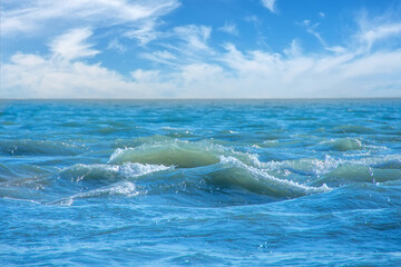 Restless exciting surface of the sea on a cloudy sunny day.