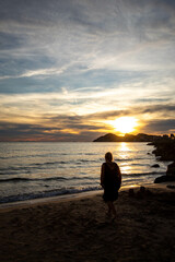 Fototapeta premium Mujer solitaria reflexionando sobre el amor en un día muy especial mientras observa el atardecer a la orilla del tranquilo mar.
