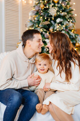 happy family. mom, dad and son on the couch by the Christmas tree.