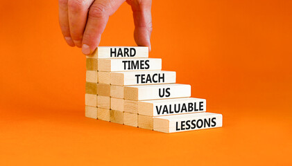 Lesson from hard times symbol. Concept words Hard times teach us valuable lessons on wooden blocks on a beautiful orange background. Businessman hand. Business lesson from hard times concept.