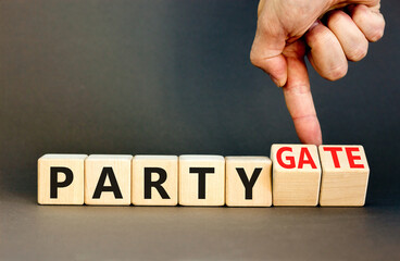Party and partygate symbol. Concept words Party and Partygate on wooden cubes. Businessman hand. Beautiful grey table grey background. Business party and partygate concept. Copy space.