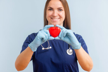 Female doctor with stethoscope holding red heart on blue background