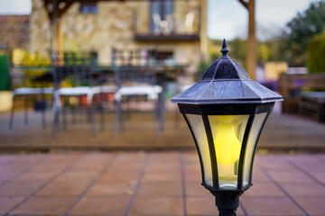 Garden lamp lit at sunset with the country house in the background.