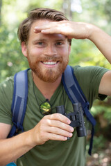 guy looking at binoculars in forest