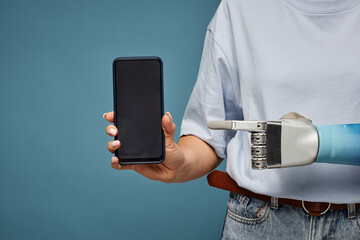 Cropped image of woman with bionic hand pointing at smartphone screen