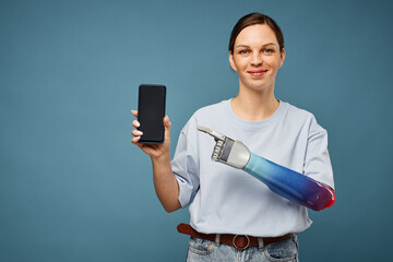 Happy young woman with prosthetic arm pointing at smartphone screen recommending new app