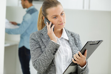 female realtor with clipboard on the phone