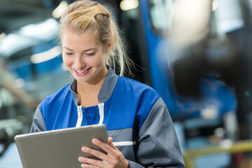 female worker wearing overalls using tablet computer