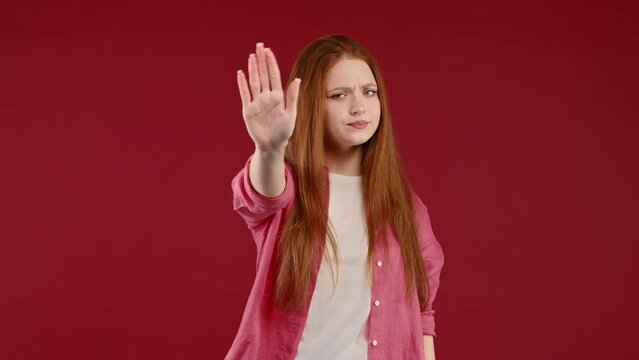 Uninterested woman disapproving with NO hand sign gesture. Denying, rejecting, disagree. Portrait of young lady on red background, timeout concept.
