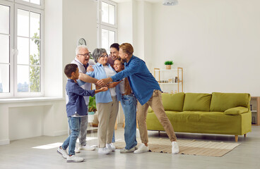 Obraz premium Happy large cute family hugging their beloved grandmother in a cozy bright spacious room at home. Concept of a dynasty in three generations, family ties, unconditional love, family relations, reunion.