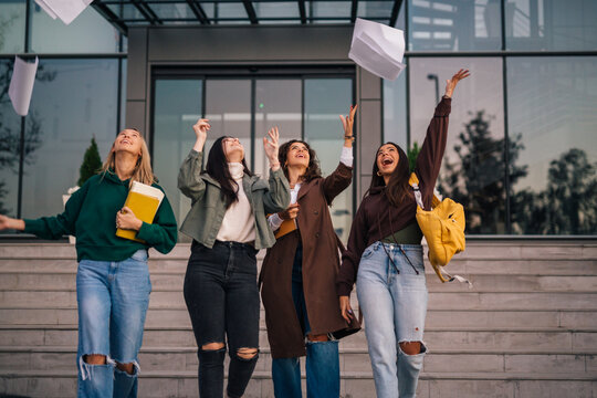 Happy friends throw away their notes for the exam