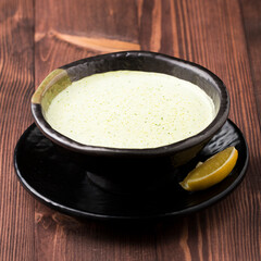 Creamy broccoli soup and lemon slice served in bowl isolated on table top view soup