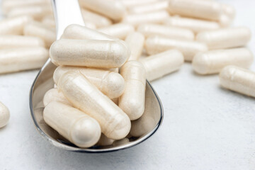 White medicine capsules, vitamin pills or drugs in a spoon, medication treatment, health care concept