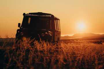 Romantischer Blick - Geländewagen im Licht der untergehenden Sonne am Straßenrand in der Nähe von Aus, Namibia © Michael
