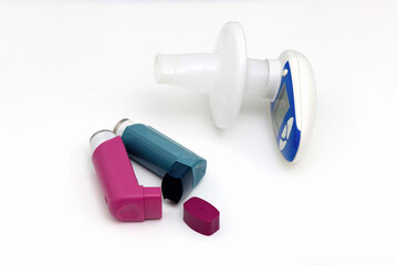 Asthma medications inhalers and peak flow meter on a white background.